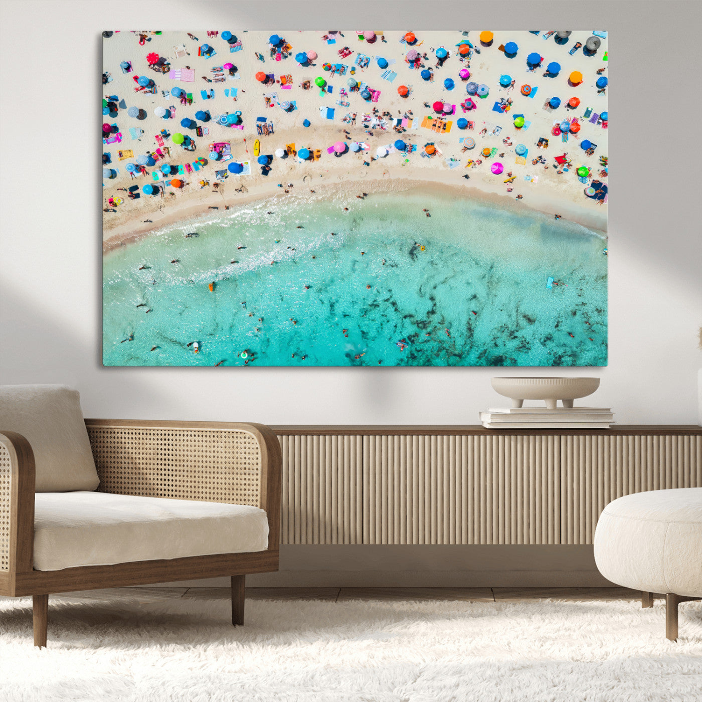 Aerial view of a vibrant beach filled with colorful umbrellas and people enjoying the turquoise ocean, capturing a lively summer vacation scene.