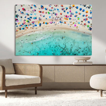 Aerial view of a vibrant beach filled with colorful umbrellas and people enjoying the turquoise ocean, capturing a lively summer vacation scene.