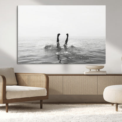A black and white minimalist water scene capturing a playful splash as a swimmer dives upside down, creating a carefree and artistic aquatic aesthetic.