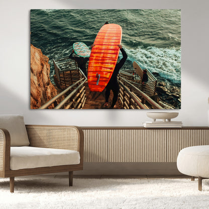 A surfer carrying a bold orange surfboard down a rugged staircase toward the ocean, bathed in golden hour light, capturing the energy of coastal adventure.