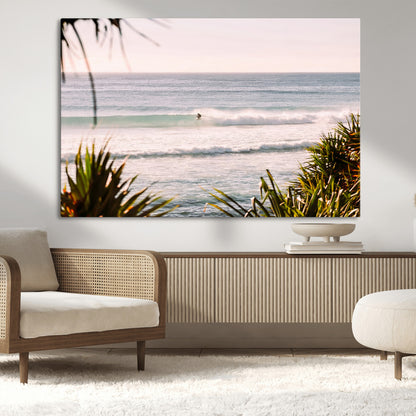 Canvas of a lone surfer riding a pastel wave at sunrise, perfect for tropical or coastal-themed spaces with a relaxed, airy vibe.