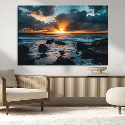 An awe-inspiring sunset over the ocean with rays of light piercing through dramatic clouds, creating a beautiful seascape with rocks in the foreground.