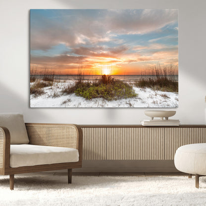 A tranquil beach scene featuring golden sunset hues over the water, with grasses in the foreground and a peaceful, serene atmosphere.