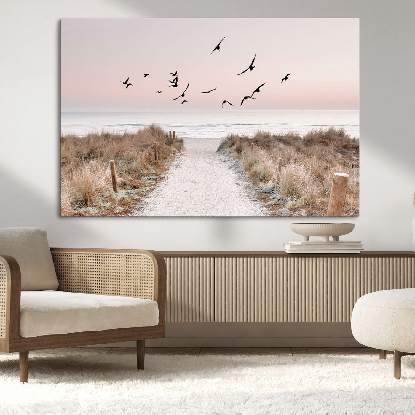 A peaceful coastal pathway leading to the ocean, with birds flying across a soft pastel sky, creating a calm and scenic beach atmosphere.