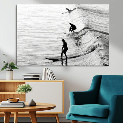 Black and white photo of surfers riding waves in a moody, high-contrast scene, ideal for modern coastal or surf-inspired home decor.