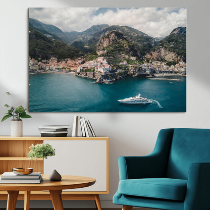 Aerial view of Amalfi Coast, Italy, with colorful hillside houses, lush green mountains, and a luxury yacht sailing in turquoise waters.