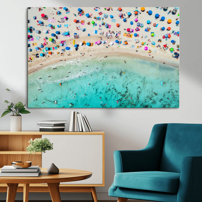 Aerial view of a vibrant beach filled with colorful umbrellas and people enjoying the turquoise ocean, capturing a lively summer vacation scene.