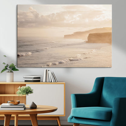 Golden hour seascape with misty cliffs and gentle waves rolling towards the shore, capturing a tranquil and warm coastal atmosphere.