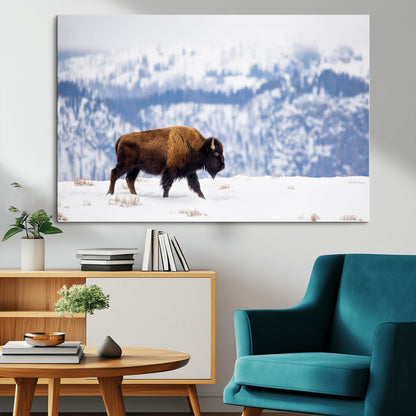 A lone bison walks across snowy ground with blue-toned mountain range behind, ideal for rustic or western farmhouse interiors.