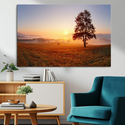 A tranquil landscape at sunrise with a mist-covered field and a lone tree, creating a peaceful and natural atmosphere.