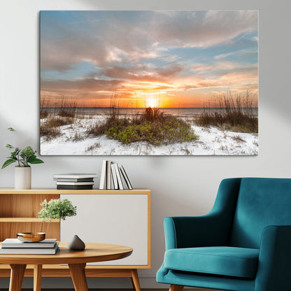 A tranquil beach scene featuring golden sunset hues over the water, with grasses in the foreground and a peaceful, serene atmosphere.