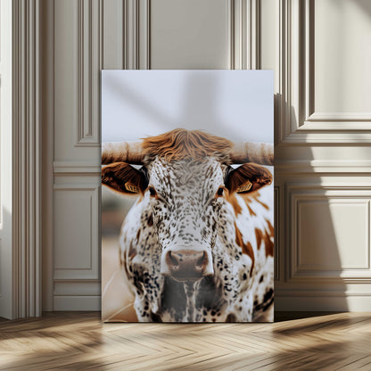 Close-up of a speckled Texas longhorn with wide horns and a bold gaze, perfect for rustic or country-style decor in warm tones.