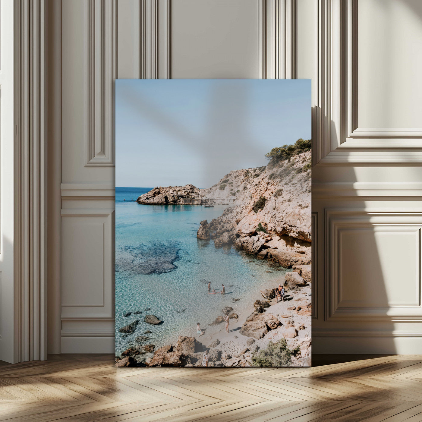 A vibrant coastal photo of a rocky Mediterranean cove with turquoise waters and beachgoers, ideal for boho coastal or summer-inspired interiors.