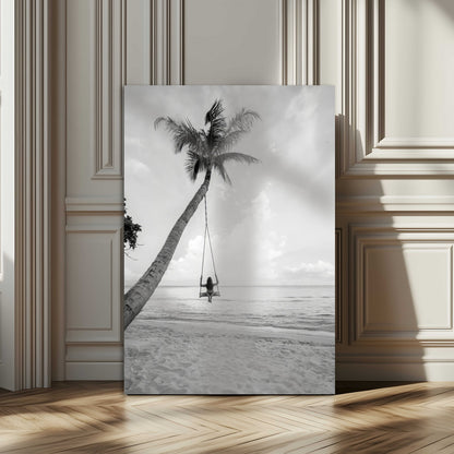 Monochrome photo of a woman swinging from a palm tree on a serene beach, ideal for minimalist or tropical coastal decor.