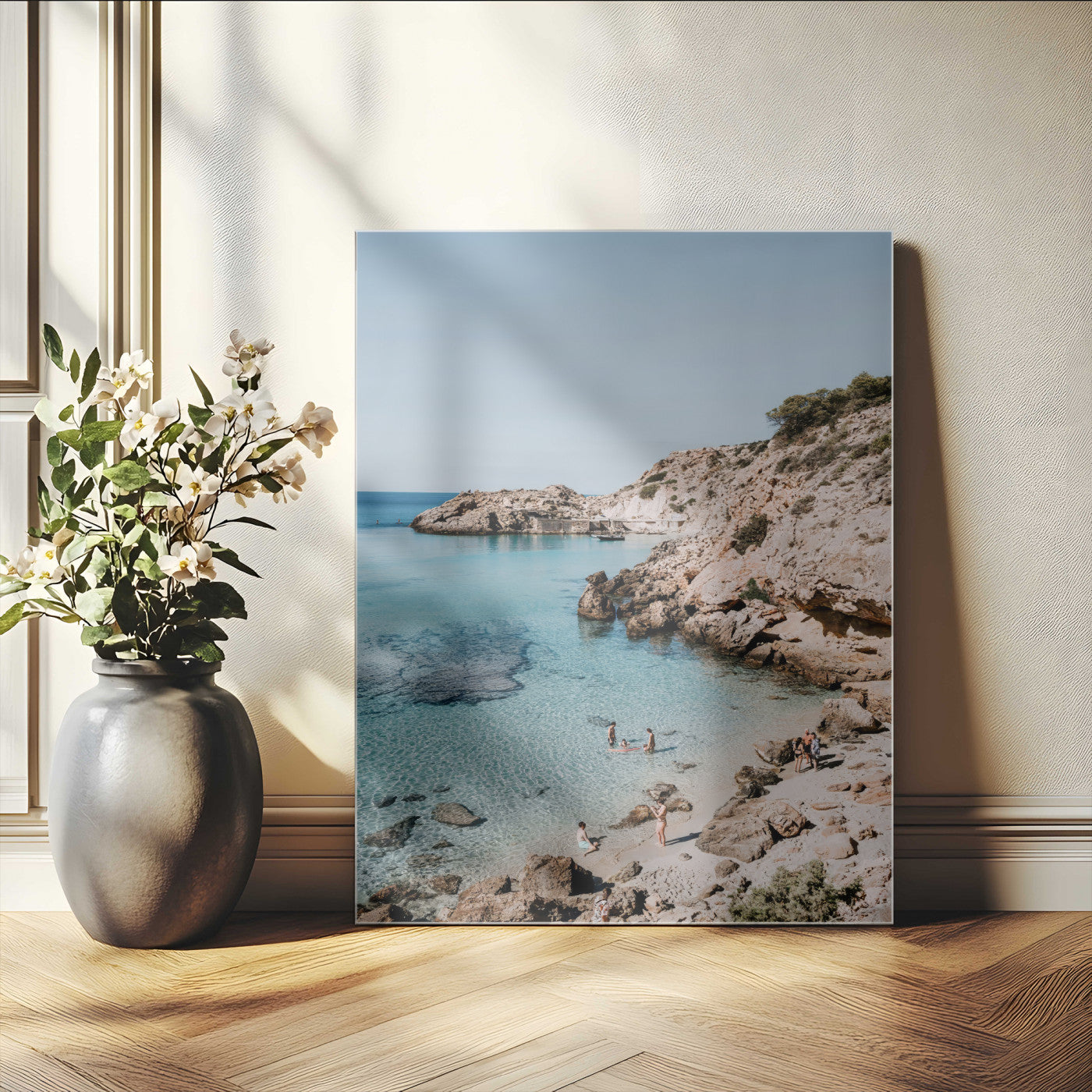 A vibrant coastal photo of a rocky Mediterranean cove with turquoise waters and beachgoers, ideal for boho coastal or summer-inspired interiors.