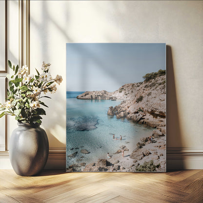 A vibrant coastal photo of a rocky Mediterranean cove with turquoise waters and beachgoers, ideal for boho coastal or summer-inspired interiors.
