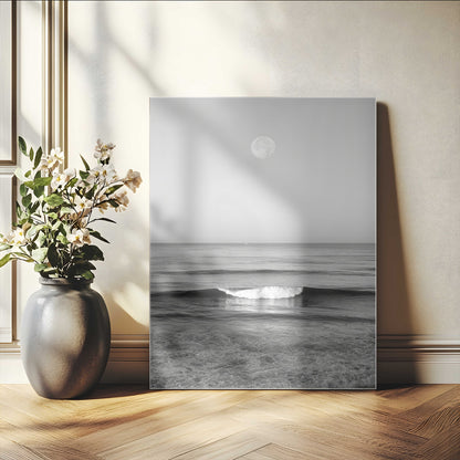 Black and white wall art of a calm ocean wave beneath a full moon, ideal for minimalist or monochrome coastal decor.