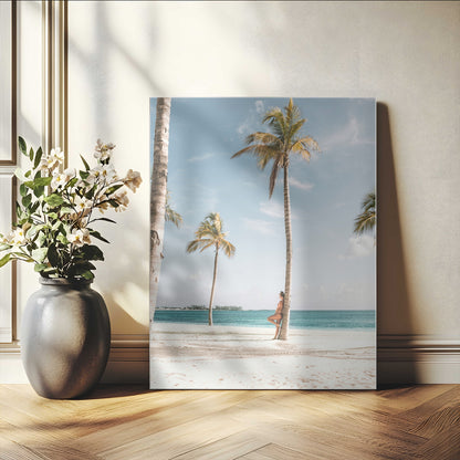 Person leaning on a palm tree at a tropical beach with white sand and turquoise water, perfect for coastal or beach-themed home decor.