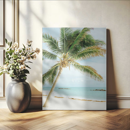 A tall palm tree leaning over a white sandy beach with turquoise ocean waves, creating a peaceful and tropical coastal scene.