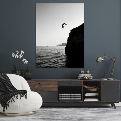 Silhouette of a person mid-air during a cliff jump over the ocean, captured in black and white for minimalist adventure decor.