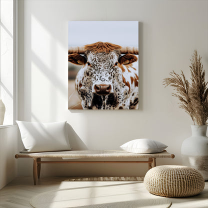 Close-up of a speckled Texas longhorn with wide horns and a bold gaze, perfect for rustic or country-style decor in warm tones.