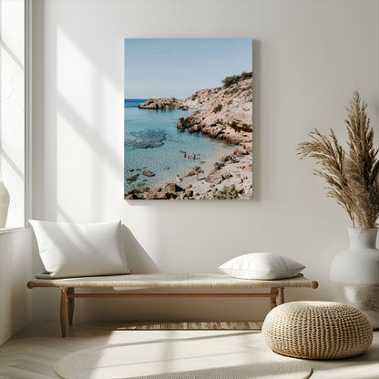 A vibrant coastal photo of a rocky Mediterranean cove with turquoise waters and beachgoers, ideal for boho coastal or summer-inspired interiors.