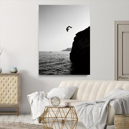 Silhouette of a person mid-air during a cliff jump over the ocean, captured in black and white for minimalist adventure decor.