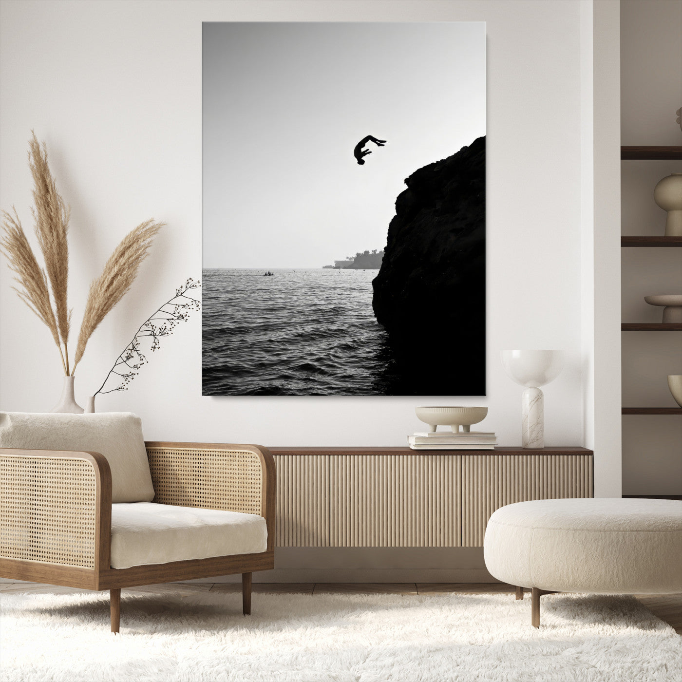 Silhouette of a person mid-air during a cliff jump over the ocean, captured in black and white for minimalist adventure decor.