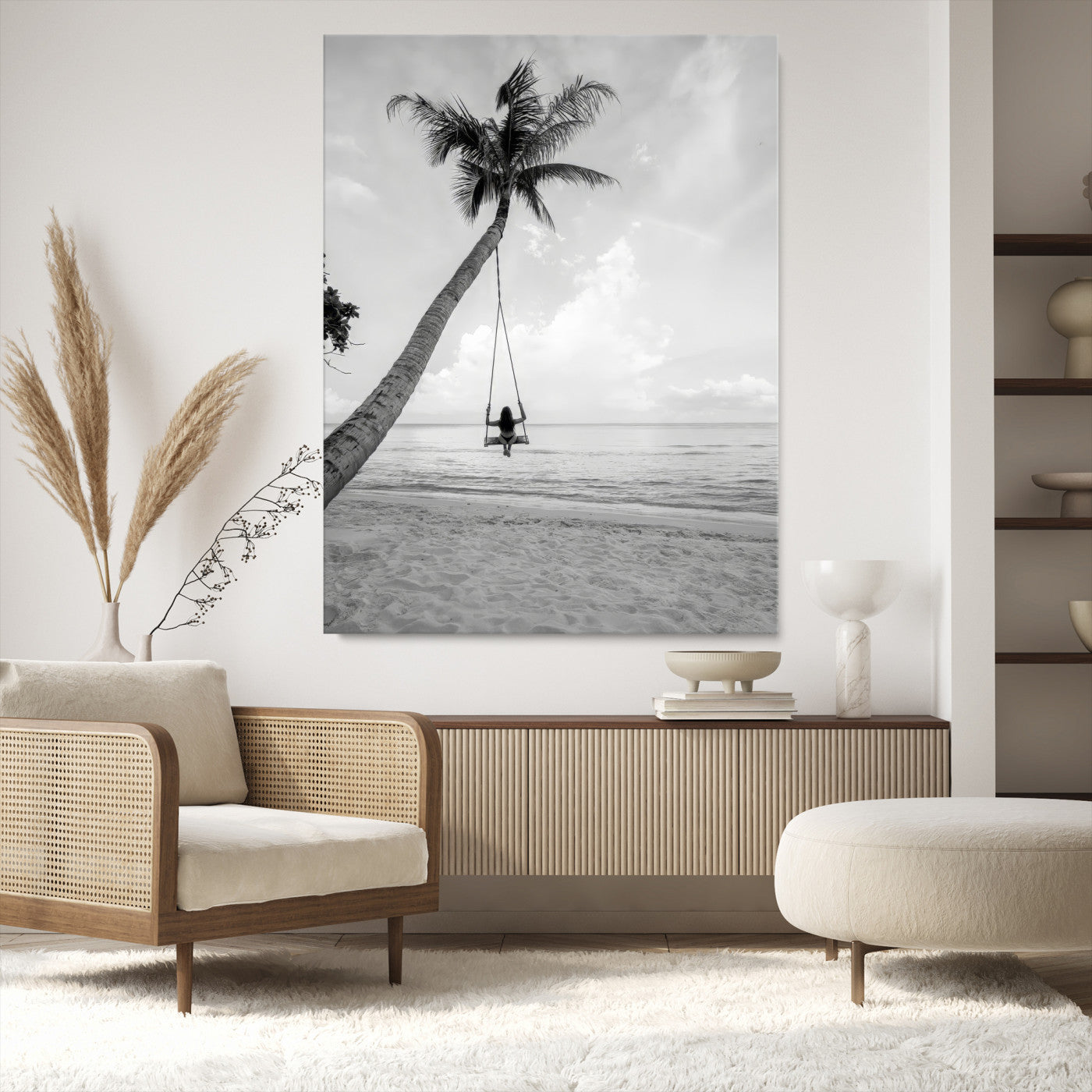 Monochrome photo of a woman swinging from a palm tree on a serene beach, ideal for minimalist or tropical coastal decor.