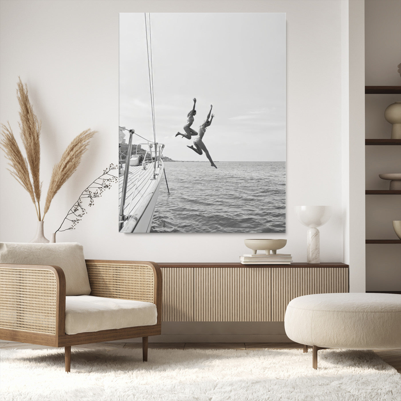 Black and white canvas wall art of two women joyfully jumping off a yacht into the sea, ideal for minimalist coastal or nautical-themed spaces.