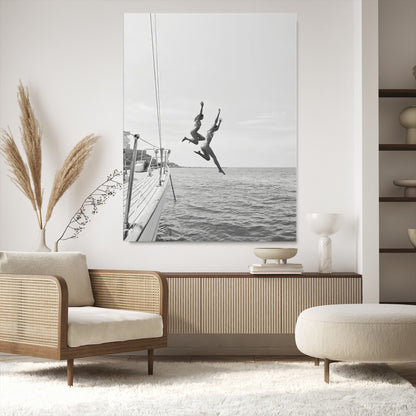 Black and white canvas wall art of two women joyfully jumping off a yacht into the sea, ideal for minimalist coastal or nautical-themed spaces.