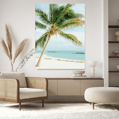 A tall palm tree leaning over a white sandy beach with turquoise ocean waves, creating a peaceful and tropical coastal scene.