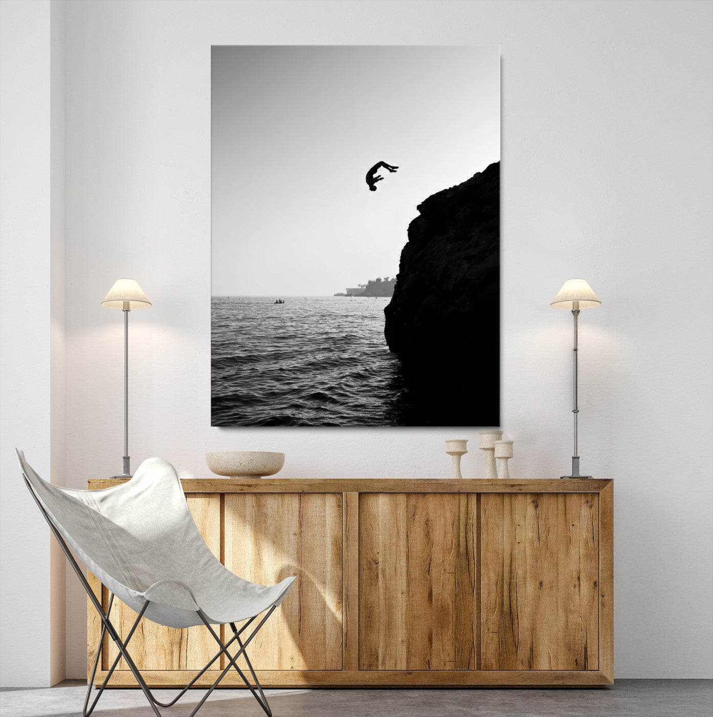 Silhouette of a person mid-air during a cliff jump over the ocean, captured in black and white for minimalist adventure decor.