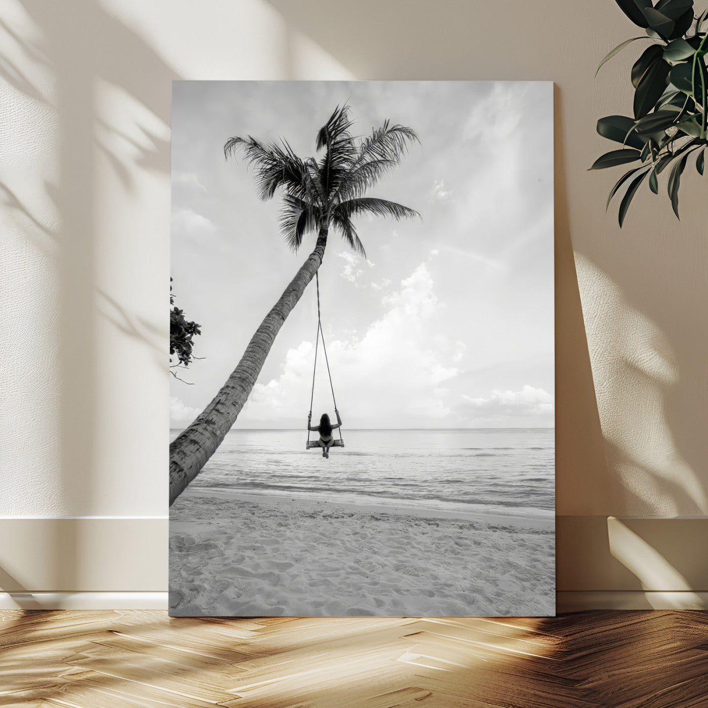 Monochrome photo of a woman swinging from a palm tree on a serene beach, ideal for minimalist or tropical coastal decor.