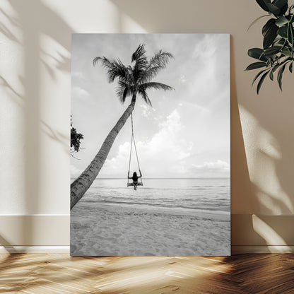 Monochrome photo of a woman swinging from a palm tree on a serene beach, ideal for minimalist or tropical coastal decor.