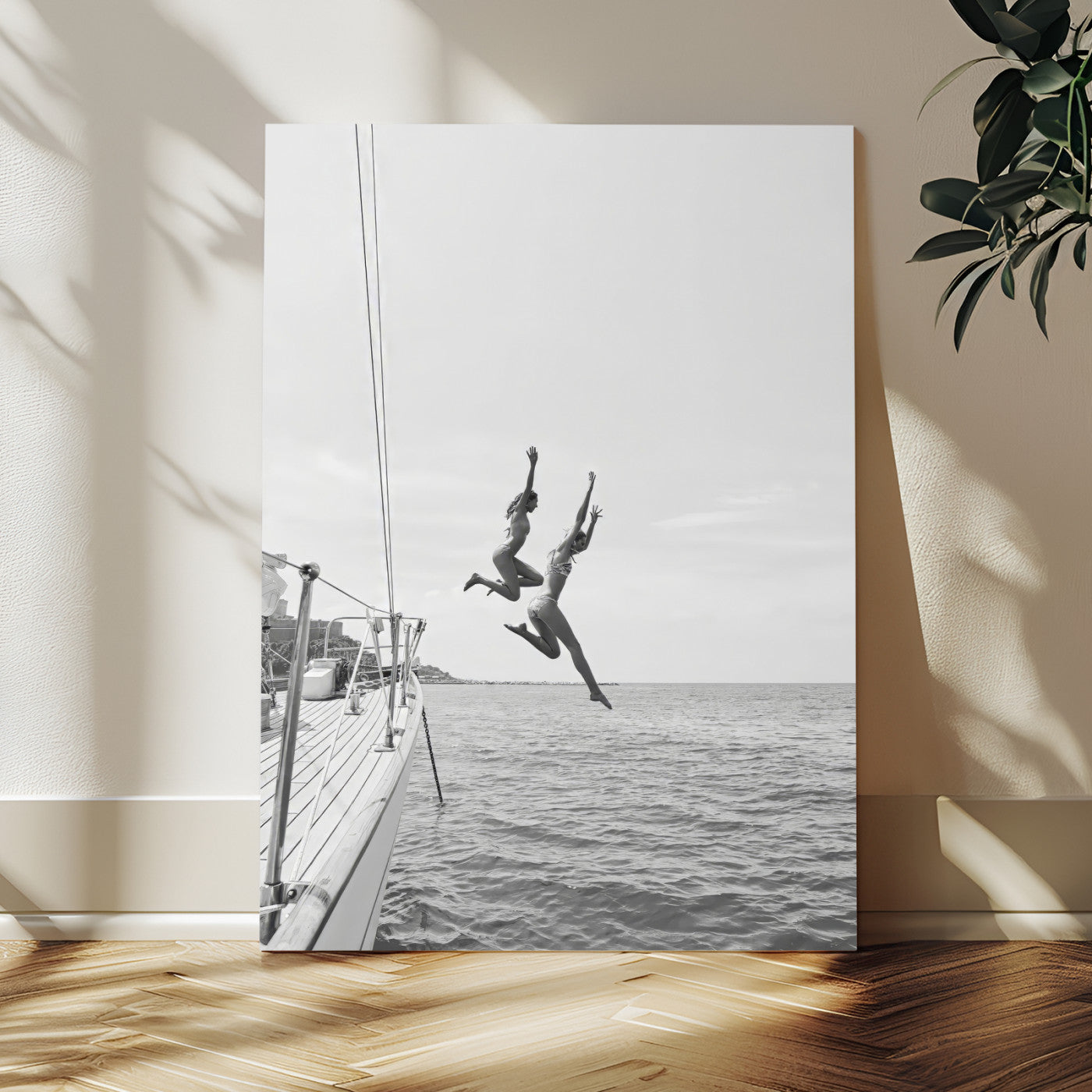 Black and white canvas wall art of two women joyfully jumping off a yacht into the sea, ideal for minimalist coastal or nautical-themed spaces.