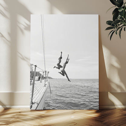 Black and white canvas wall art of two women joyfully jumping off a yacht into the sea, ideal for minimalist coastal or nautical-themed spaces.
