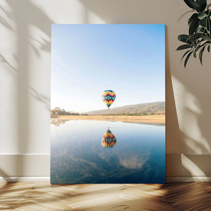 Canvas of a hot air balloon floating above a calm lake with soft reflections and vibrant sky, ideal for modern minimalist or adventure-themed home decor.