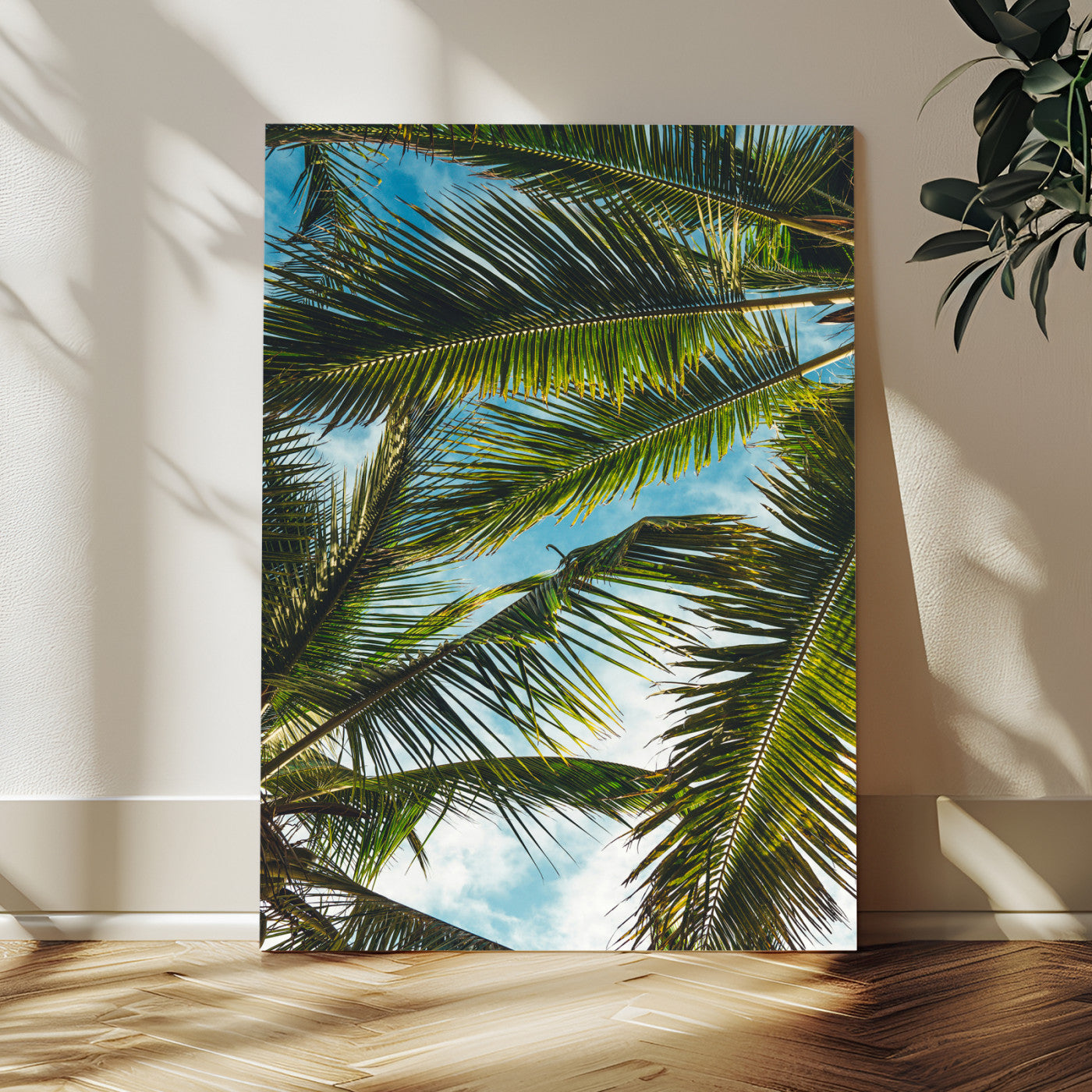 Looking up at lush green palm leaves against a bright blue sky, creating a tropical and relaxing coastal aesthetic.