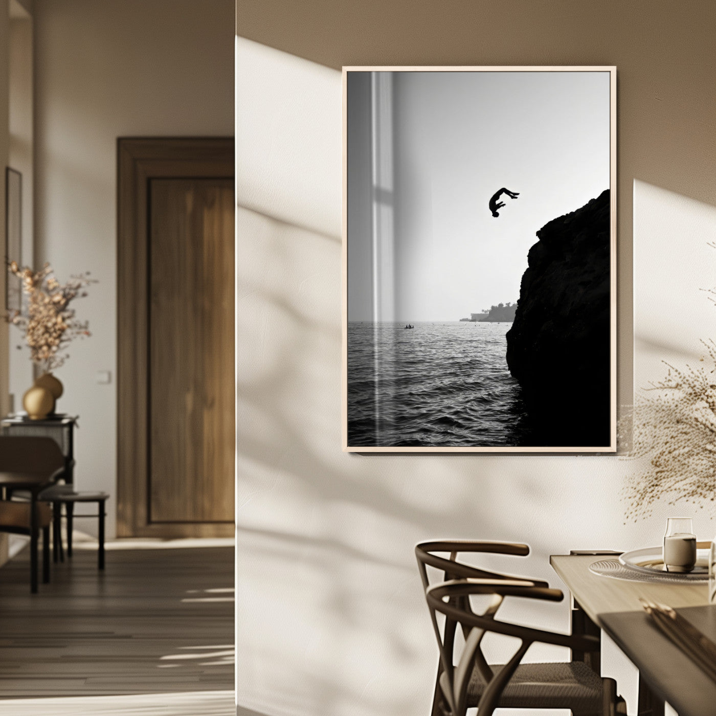 Silhouette of a person mid-air during a cliff jump over the ocean, captured in black and white for minimalist adventure decor.