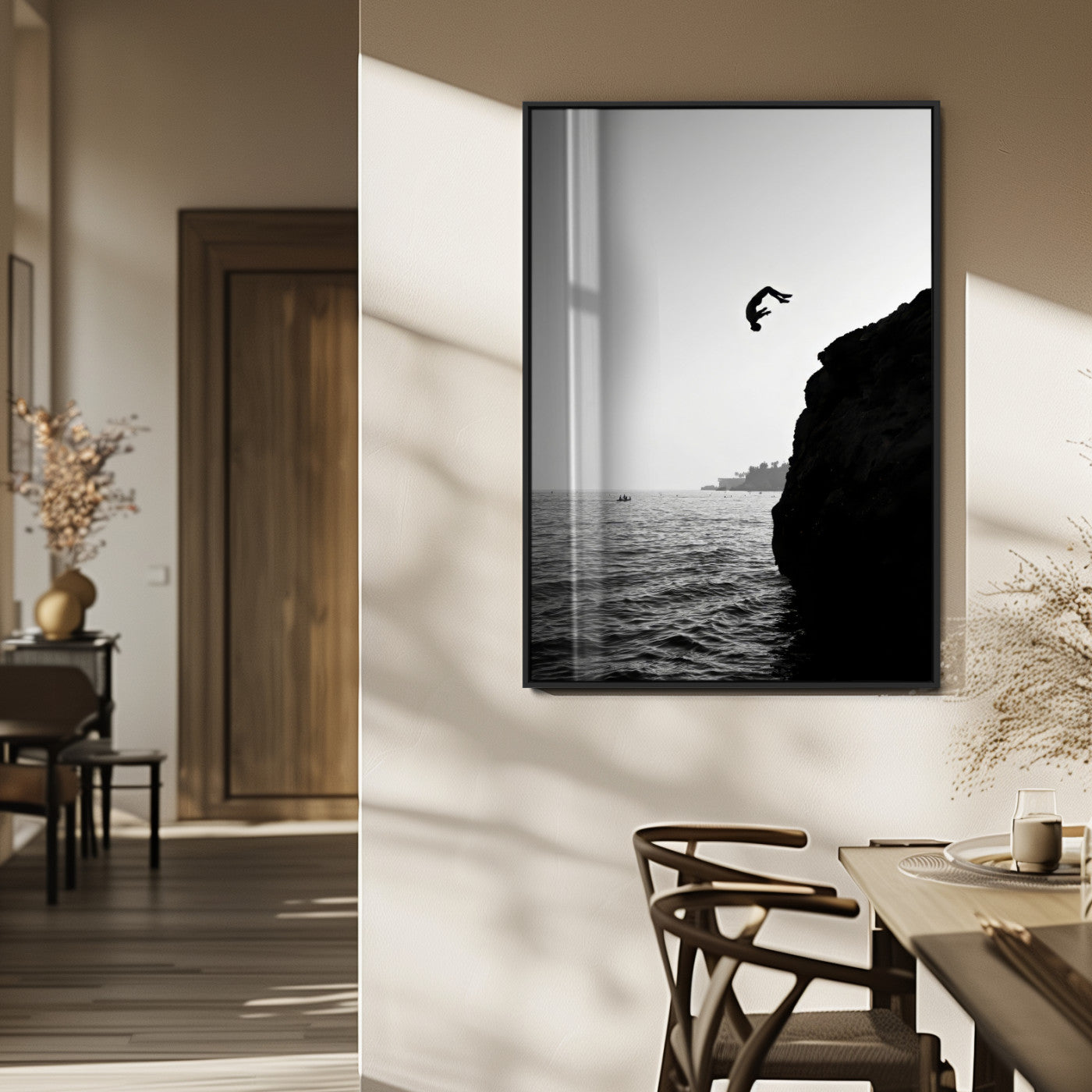 Silhouette of a person mid-air during a cliff jump over the ocean, captured in black and white for minimalist adventure decor.