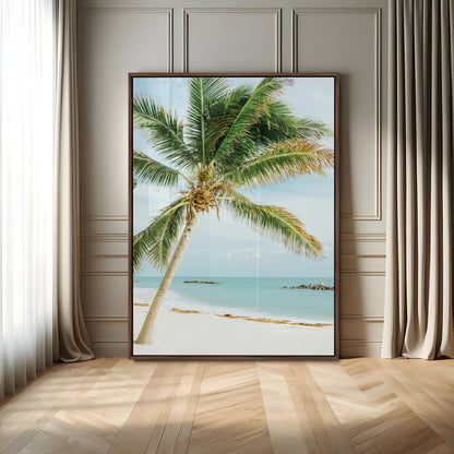 A tall palm tree leaning over a white sandy beach with turquoise ocean waves, creating a peaceful and tropical coastal scene.