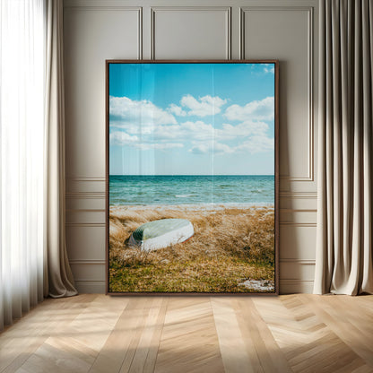 A small boat resting on a grassy shore with ocean waves and a bright blue sky, creating a peaceful coastal atmosphere.