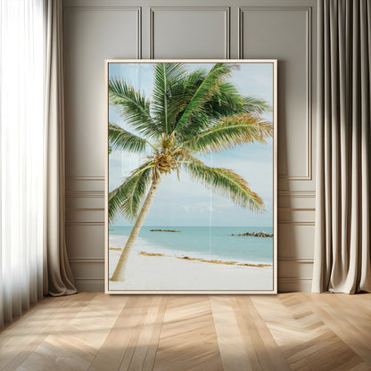 A tall palm tree leaning over a white sandy beach with turquoise ocean waves, creating a peaceful and tropical coastal scene.