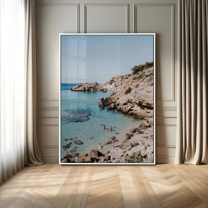 A vibrant coastal photo of a rocky Mediterranean cove with turquoise waters and beachgoers, ideal for boho coastal or summer-inspired interiors.