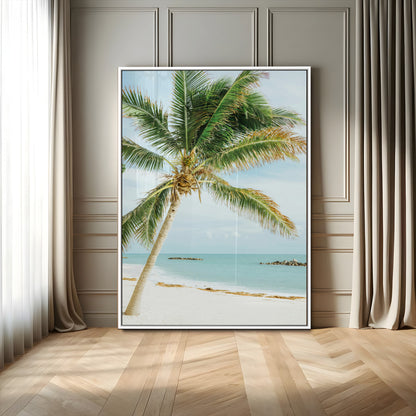 A tall palm tree leaning over a white sandy beach with turquoise ocean waves, creating a peaceful and tropical coastal scene.