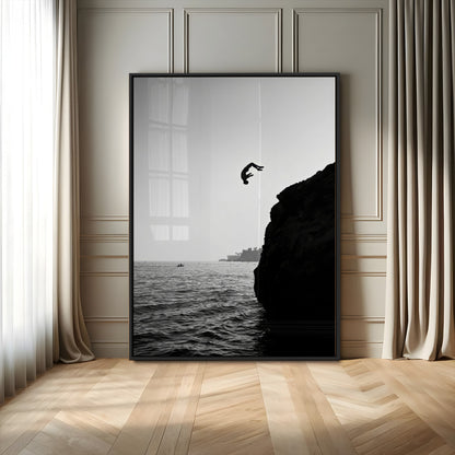 Silhouette of a person mid-air during a cliff jump over the ocean, captured in black and white for minimalist adventure decor.