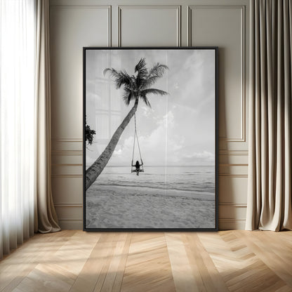 Monochrome photo of a woman swinging from a palm tree on a serene beach, ideal for minimalist or tropical coastal decor.