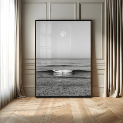 Black and white wall art of a calm ocean wave beneath a full moon, ideal for minimalist or monochrome coastal decor.