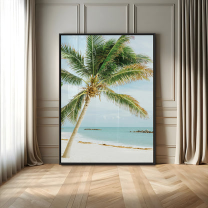 A tall palm tree leaning over a white sandy beach with turquoise ocean waves, creating a peaceful and tropical coastal scene.